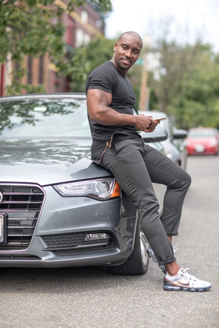 Stylish man in casual wear seated on a luxury car enjoying a sunny day.